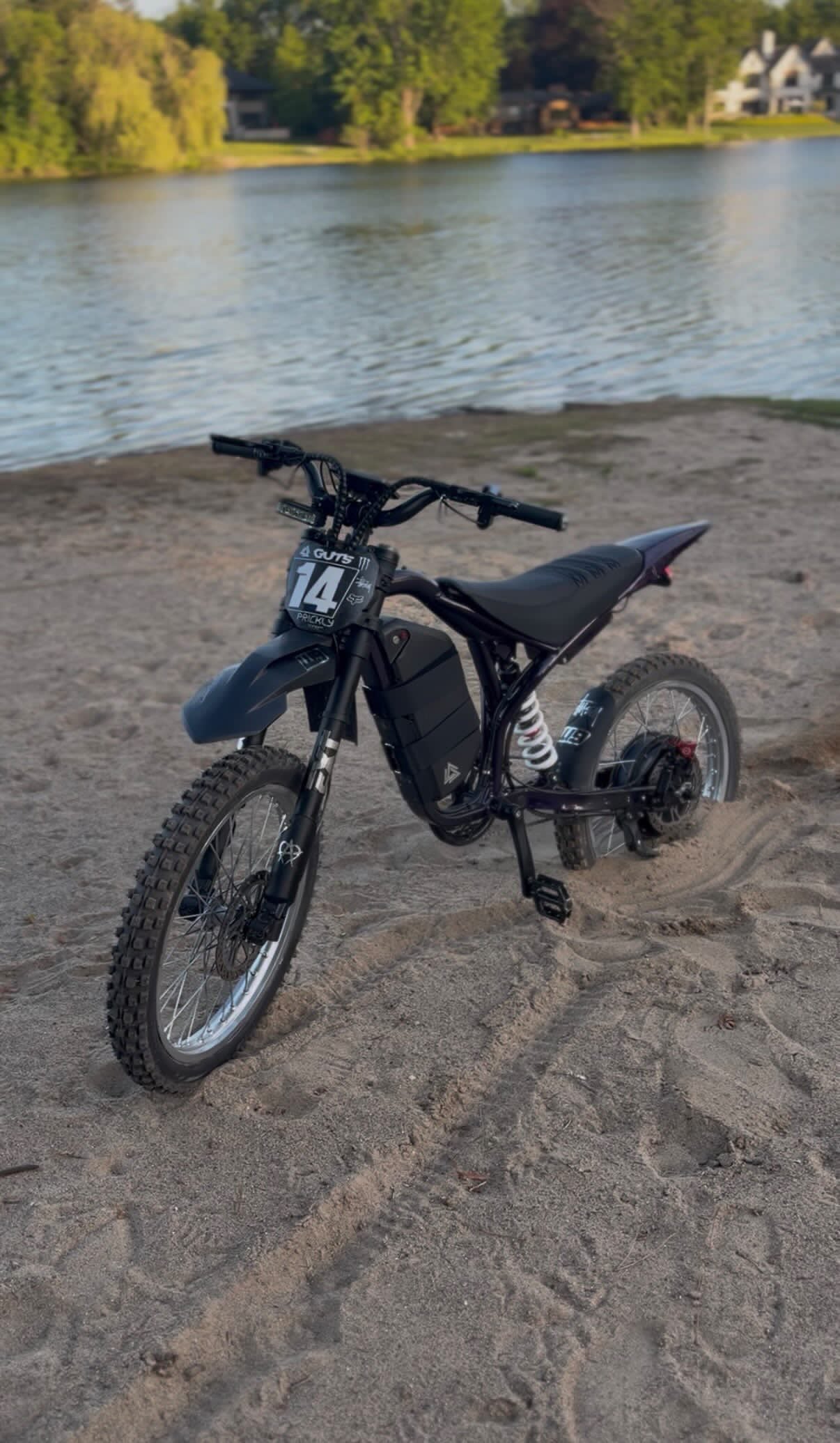 Black electric dirt bike with front disc brake and knobby tires