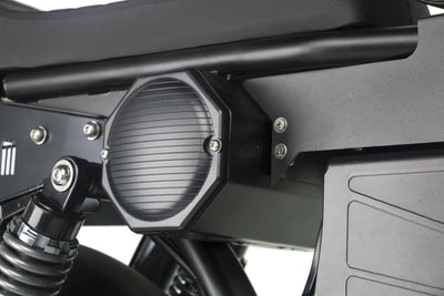 Round side light and black panel on a black electric motorcycle.
