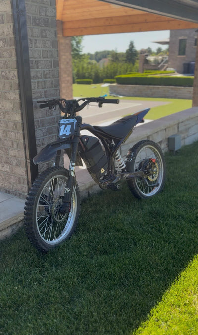 Black electric dirt bike with number plate 14 and knobby tires