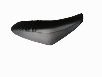 Black dirt bike seat, angled view, smooth side panels and tapered nose