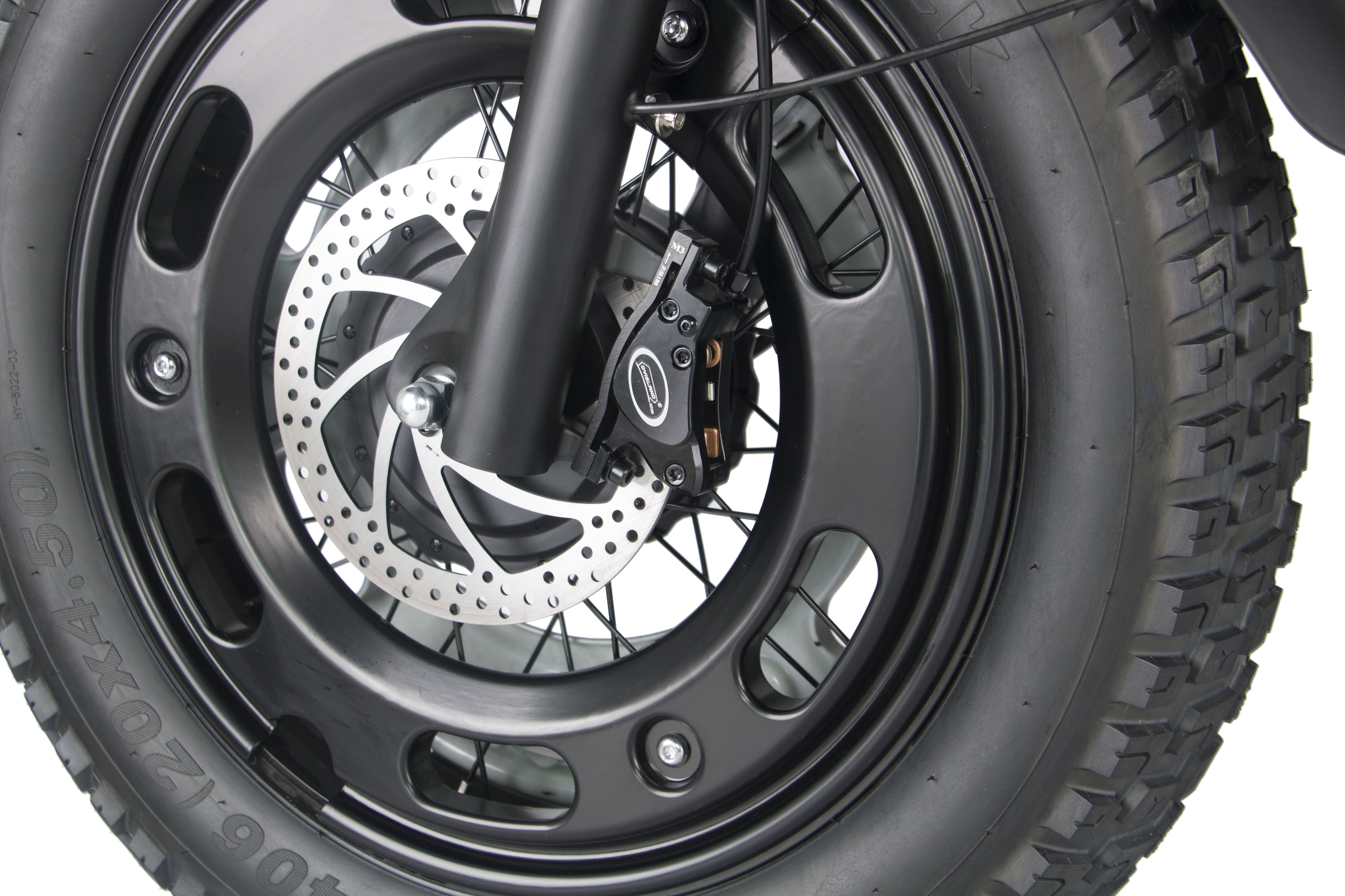 Front wheel and disc brake of a black electric motorcycle with knobby tire tread.